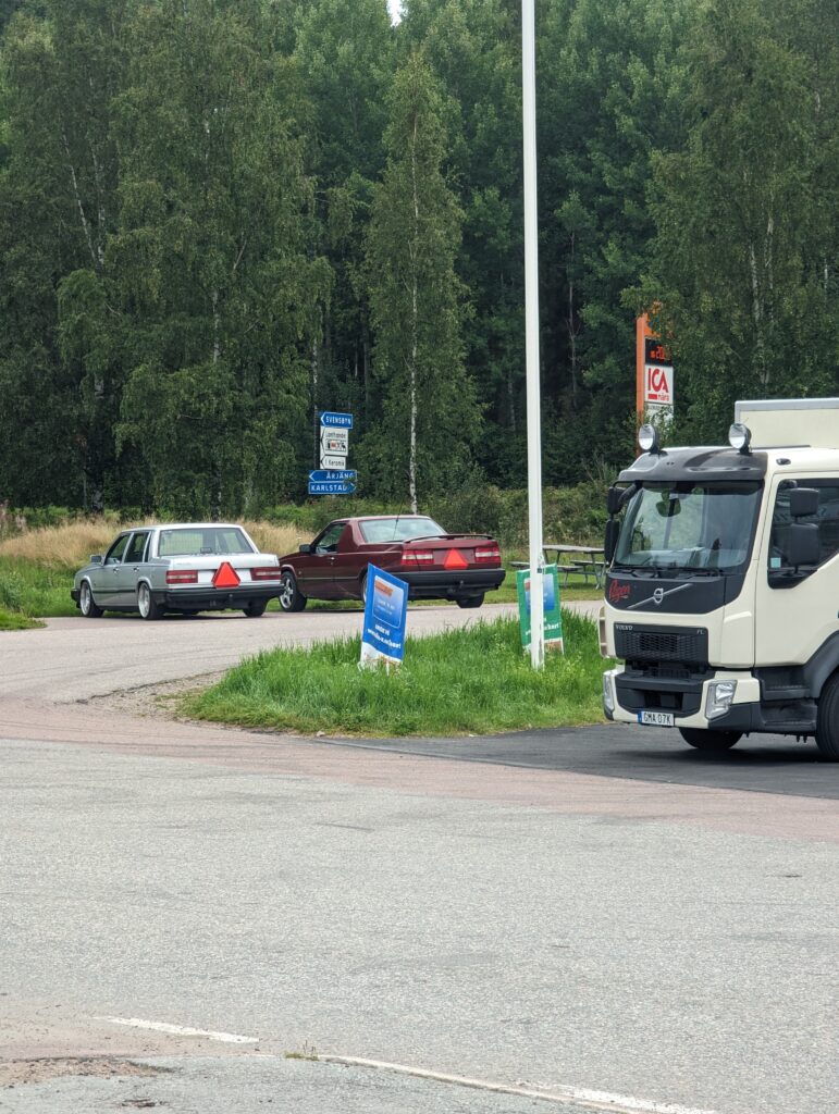 Zwei ältere Volvo aus der Ferne fotografiert, zu erkennen sind die roten Warndreiecke am Fahrzeugheck.