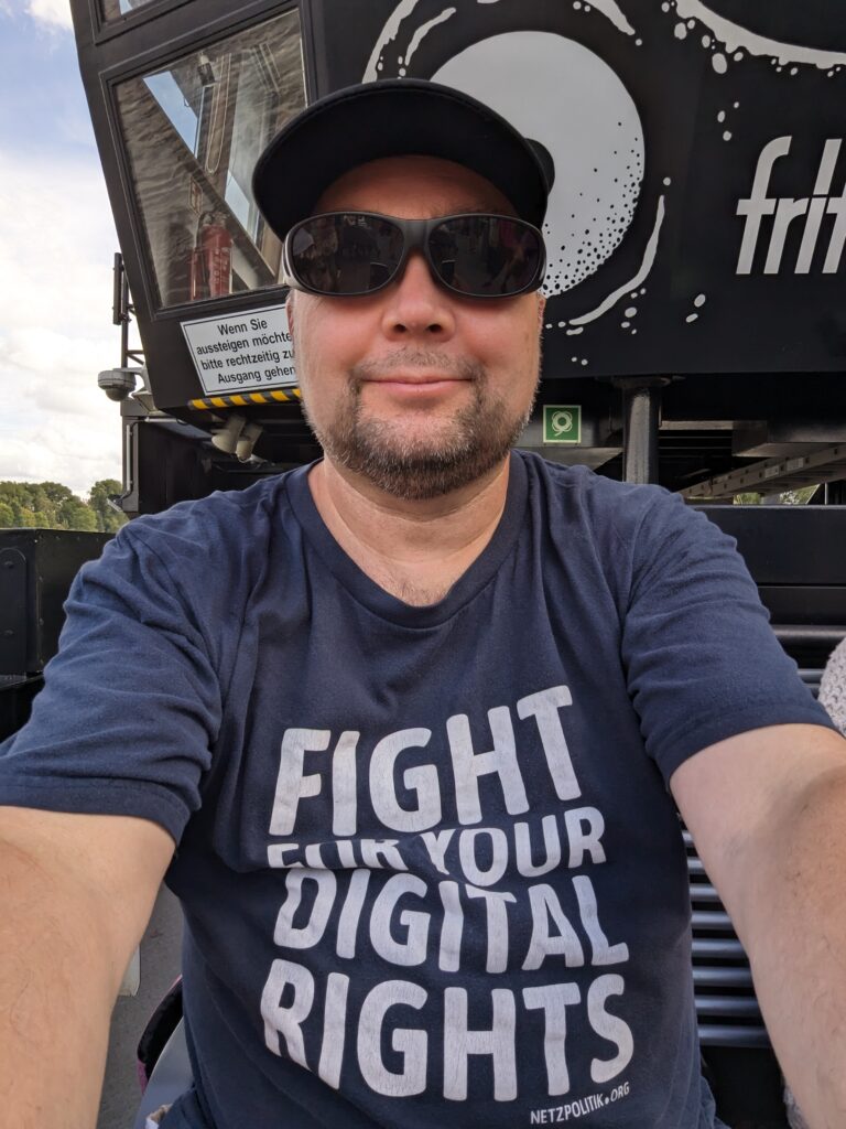 Ich mit einem Shirt mit der Aufschrift Fight for your digital rights vor einer schwarzen Schiffswand